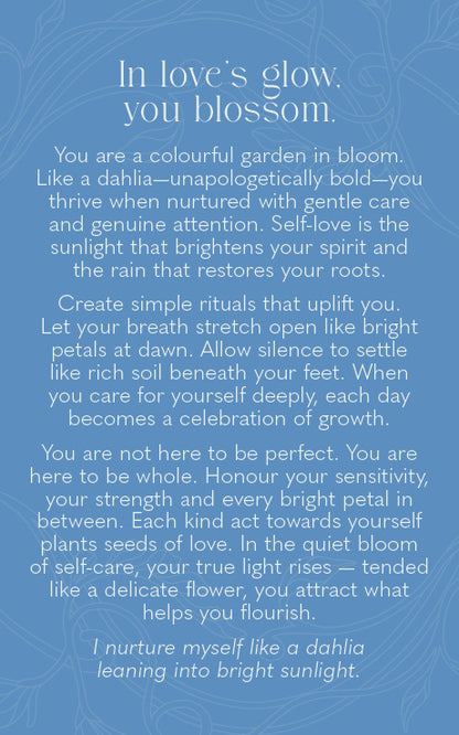 A square blue card or print with white text reading a self-help or affirmation quote about dahlia flowers and self-care, set against a matching blue patterned background.