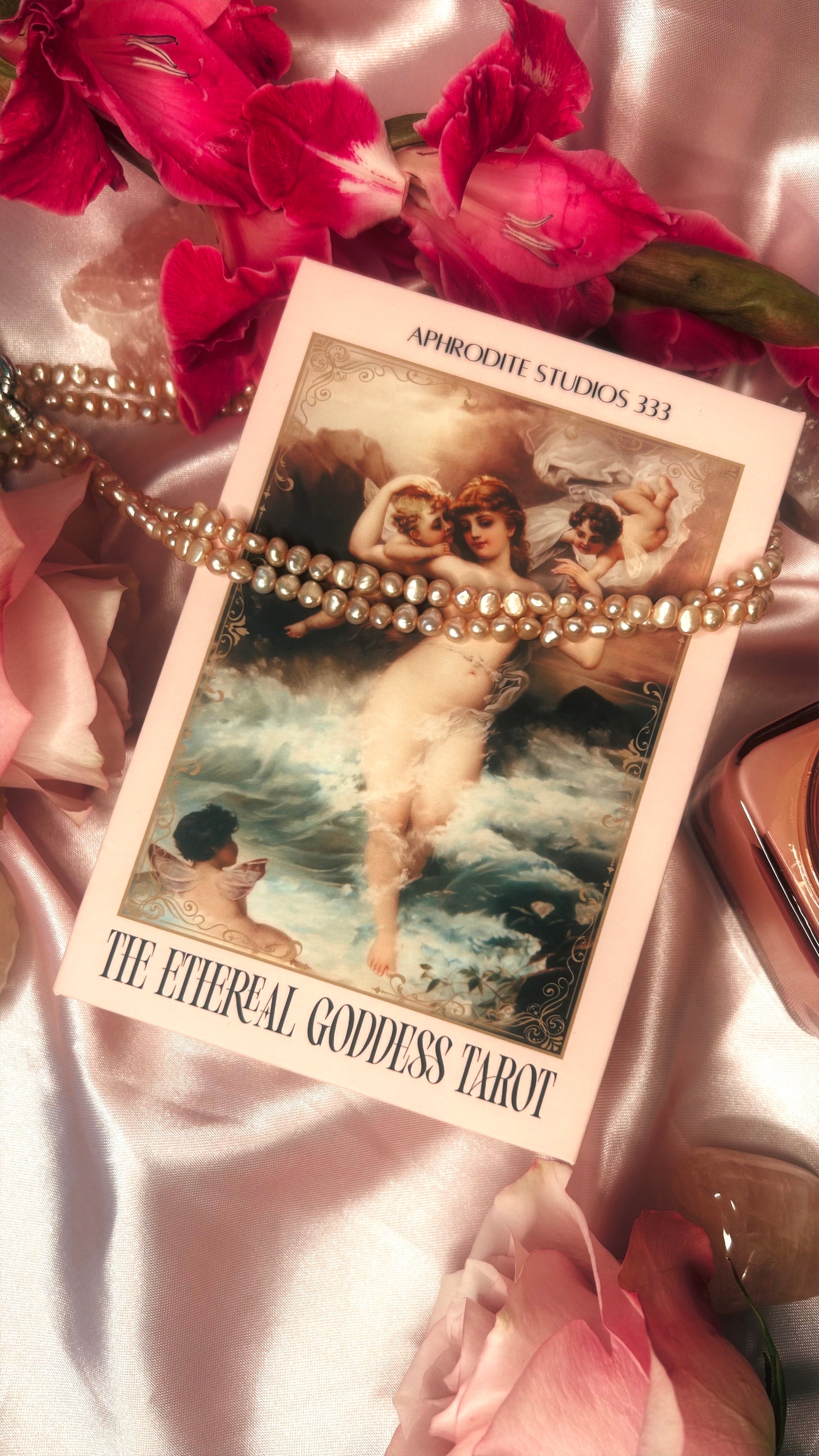 Ethereal Goddess Tarot card with pink flowers and a chain on a satin surface
