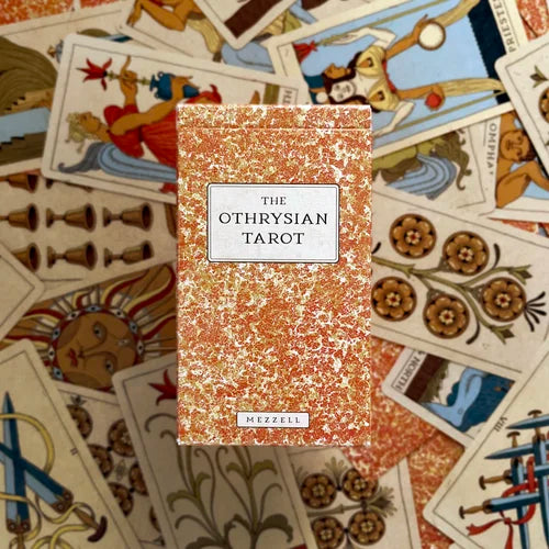 Othrysian Tarot box surrounded by tarot cards with intricate designs Set of tarot cards on a wooden surface tarot by Michael Ezzell Oneness Emporium