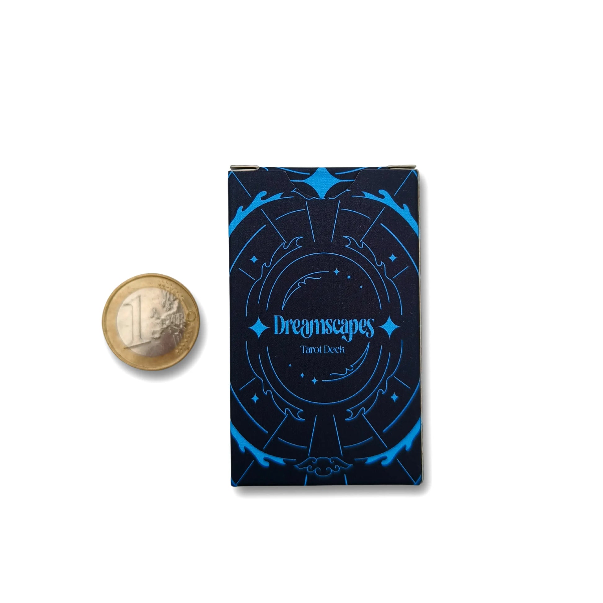 Dark blue card deck with 'Dreamscapes' text next to a gold coin for scale on a white background pocket edition