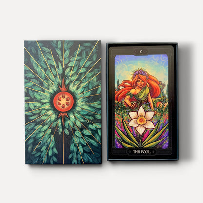 A tarot deck shown with its illustrated box on the left and a single card in a black tray on the right. The artwork features a stylized floral and radiant design in teal, green, orange, purple, and cream tones. Asphodelon Tarot by Asphodelon Studio featuring hand-painted Greek mythology artwork, gilded edges, premium matte cards and a deluxe gold foil presentation box.