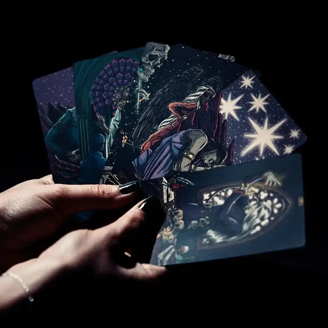 Hands holding tarot cards with star and celestial designs on a dark background Dark reflections tarot by La Muci Available at Oneness Emporium