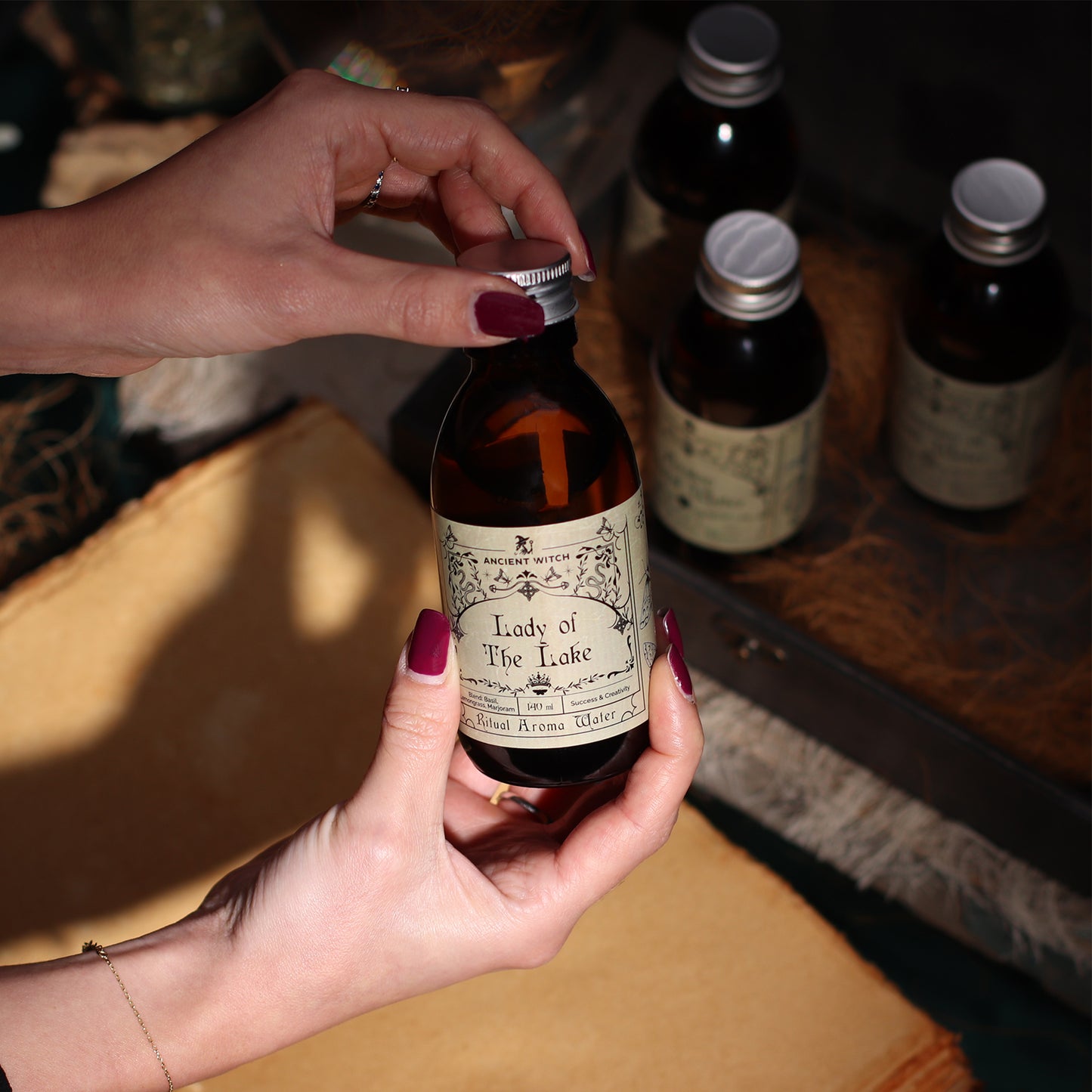 Person holding a bottle labeled 'Lady of the Lake' with other bottles in the background.