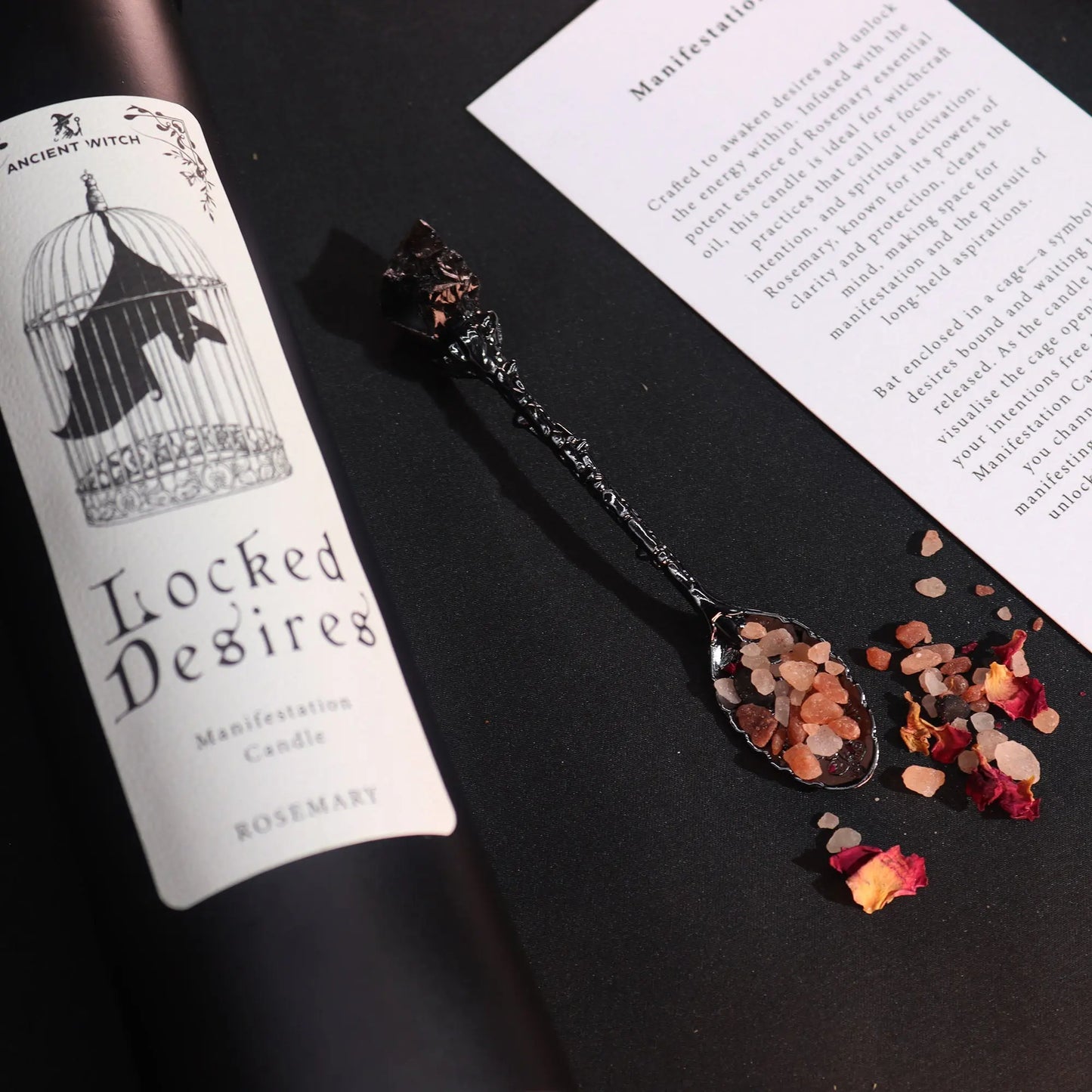 Spoon with dried herbs and petals next to a 'Locked Desires' candle label on a black surface.
