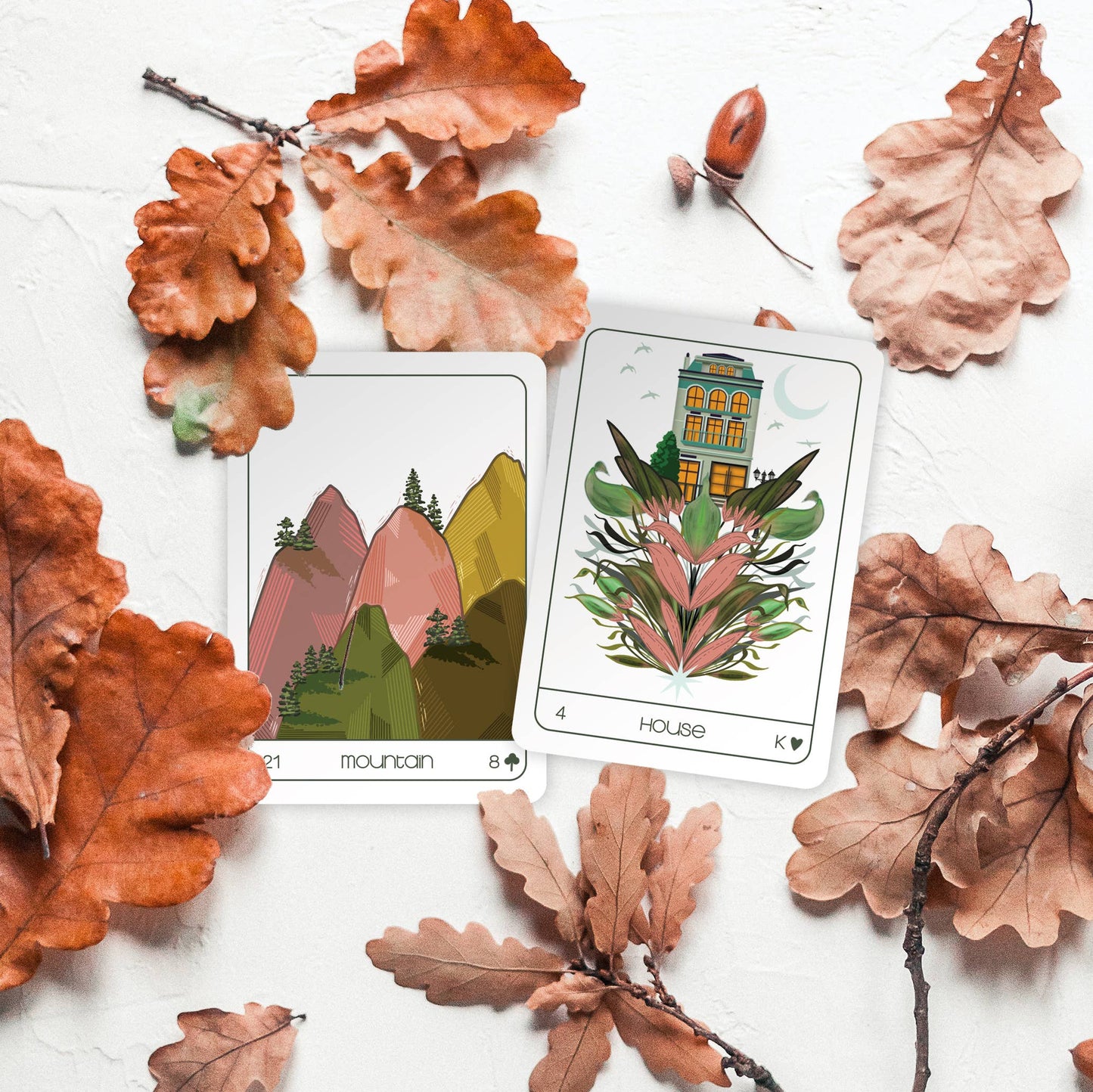 Two playing cards surrounded by autumn leaves on a white background