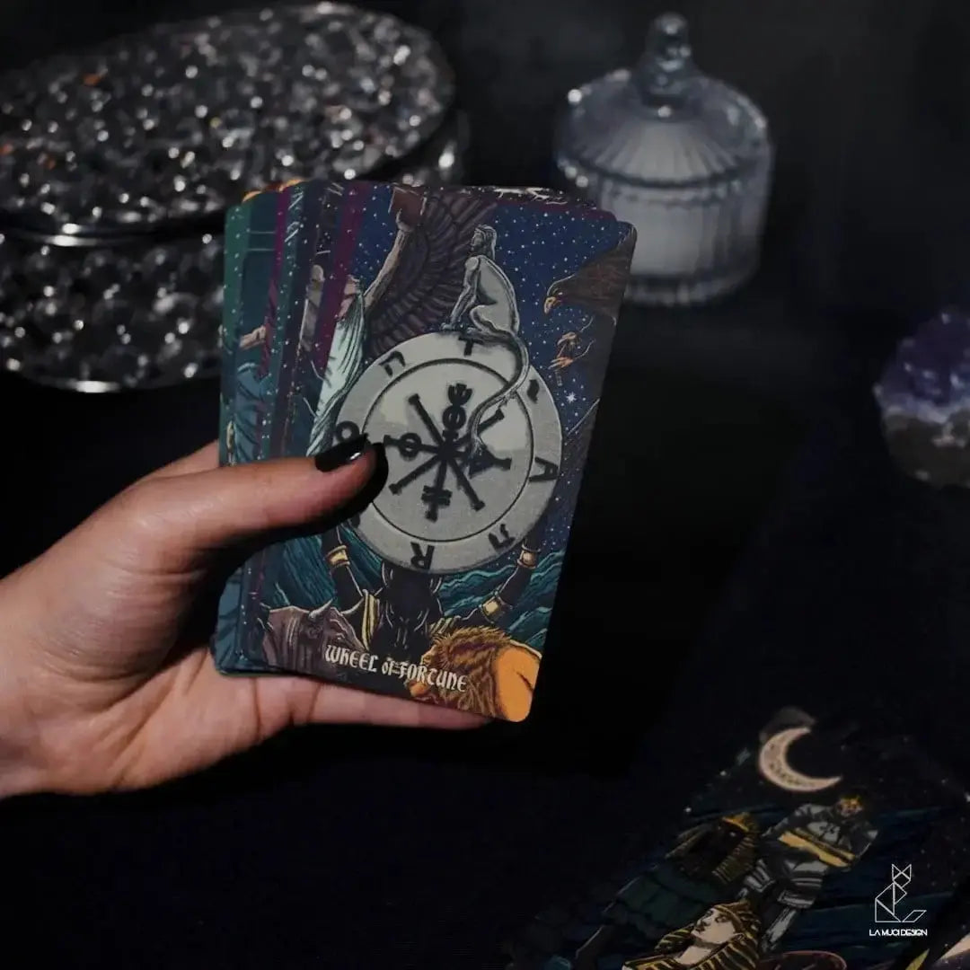 Hand holding a tarot card with intricate design against a dark background Dark reflections tarot by La Muci Available at Oneness Emporium