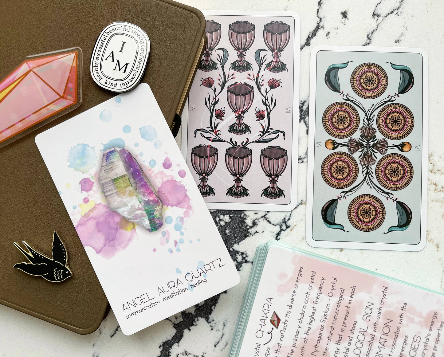 Collection of tarot cards, angel aura quartz card, and decorative items on a marble surface radiant crystal oracle