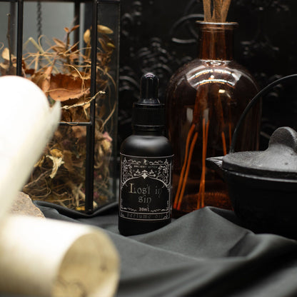 Black bottle labeled 'Lost in Sin' on a dark surface with decorative elements.