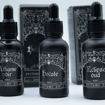 Three black perfume oil bottles with labels on a white background