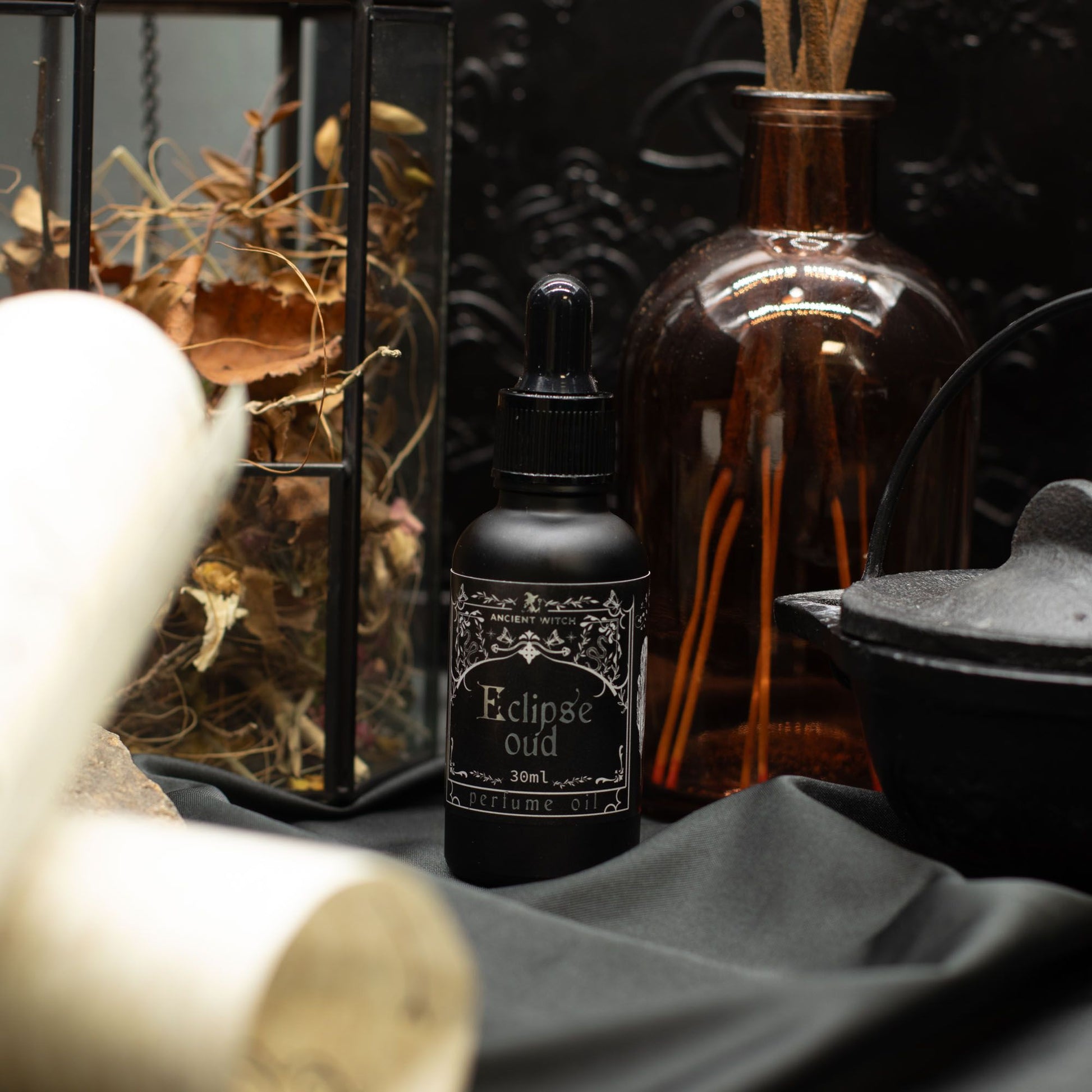 Black bottle labeled 'Eclipse Oud' with decorative elements in the background