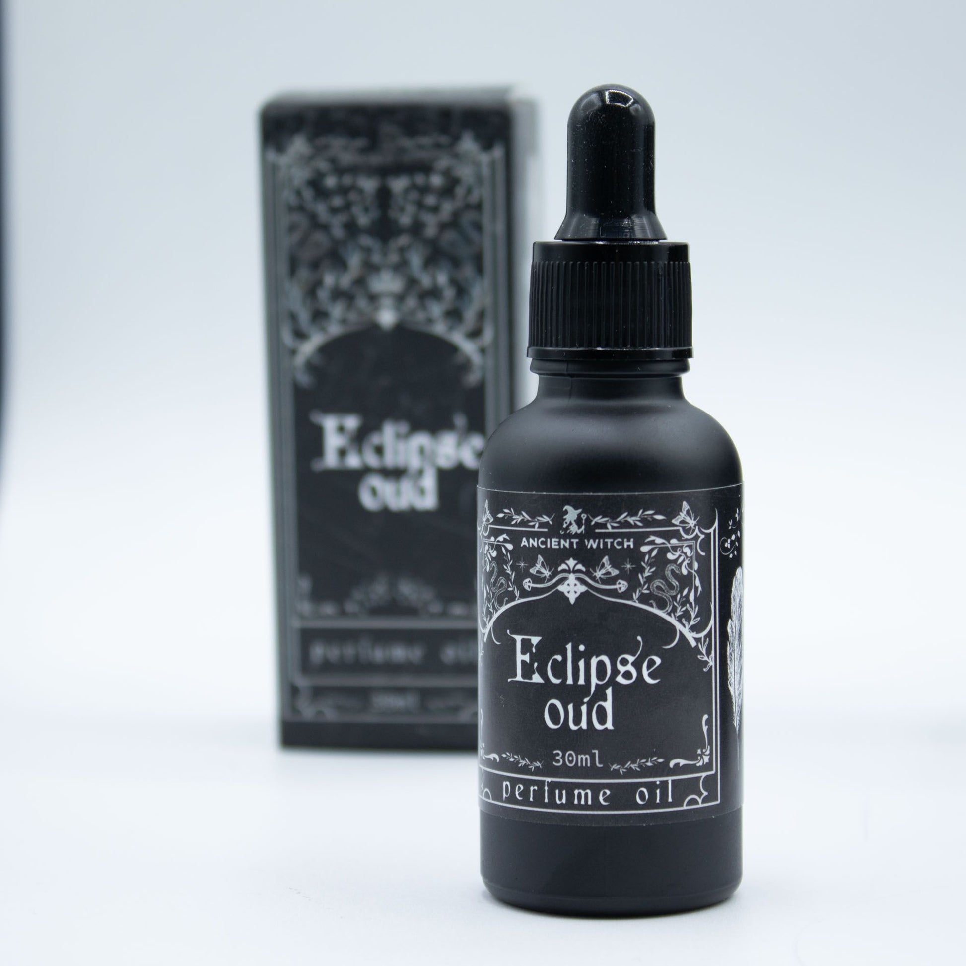Black bottle of Eclipse Oud perfume oil with dropper and packaging on a light gray background