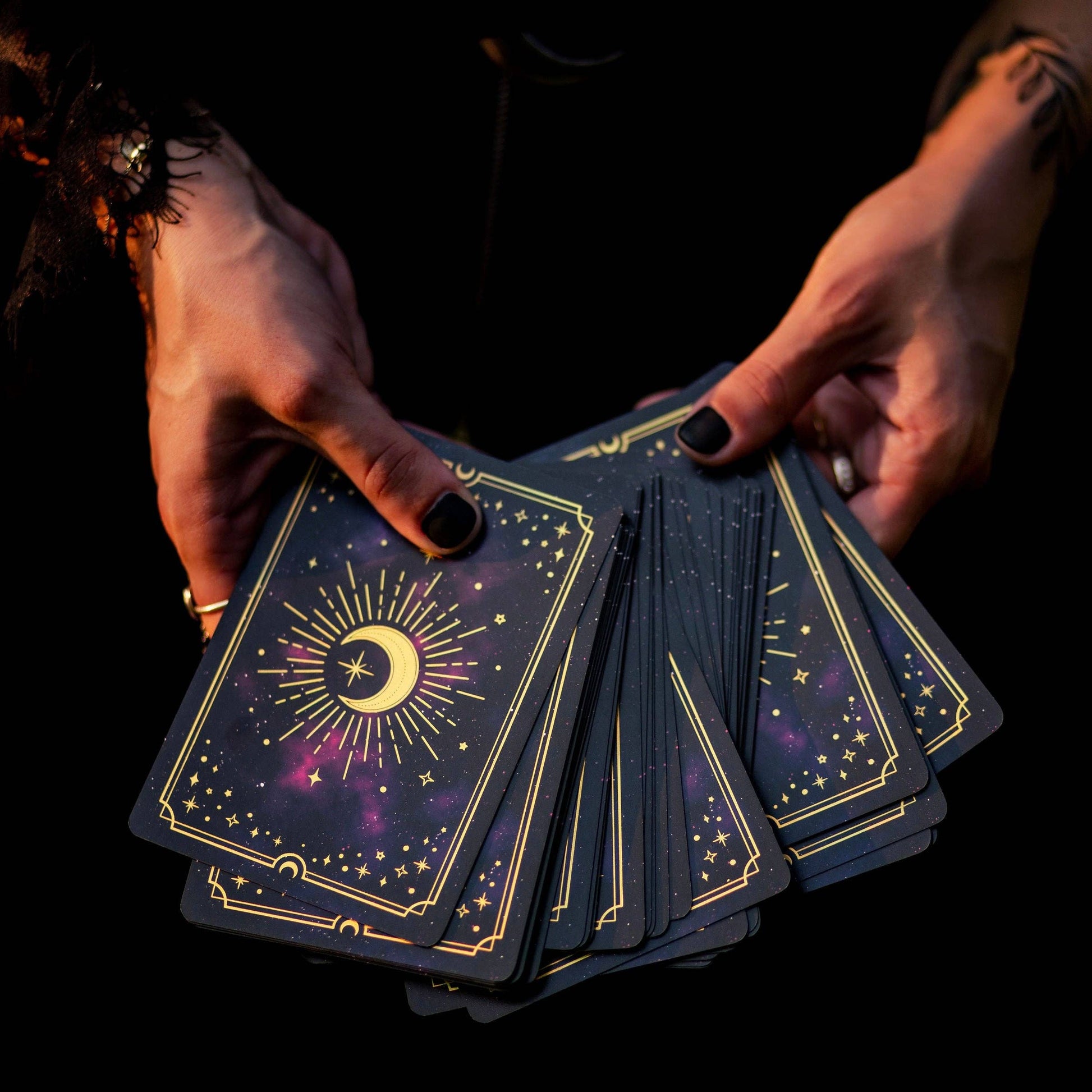 Hands holding tarot cards with star and moon design on a dark background Gold Crystal Affirmations Golden Aura Edition featuring luxury affirmation cards inspired by crystal wisdom, mindfulness, and positive daily intentions.