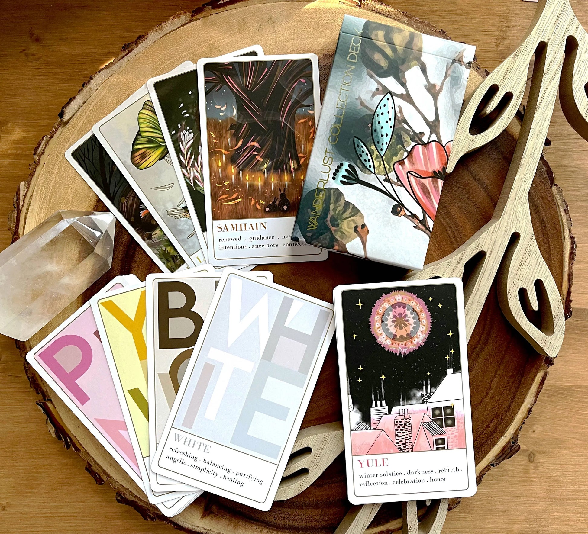 Collection of tarot cards on a wooden surface with decorative elements. Wanderlust oracle deck