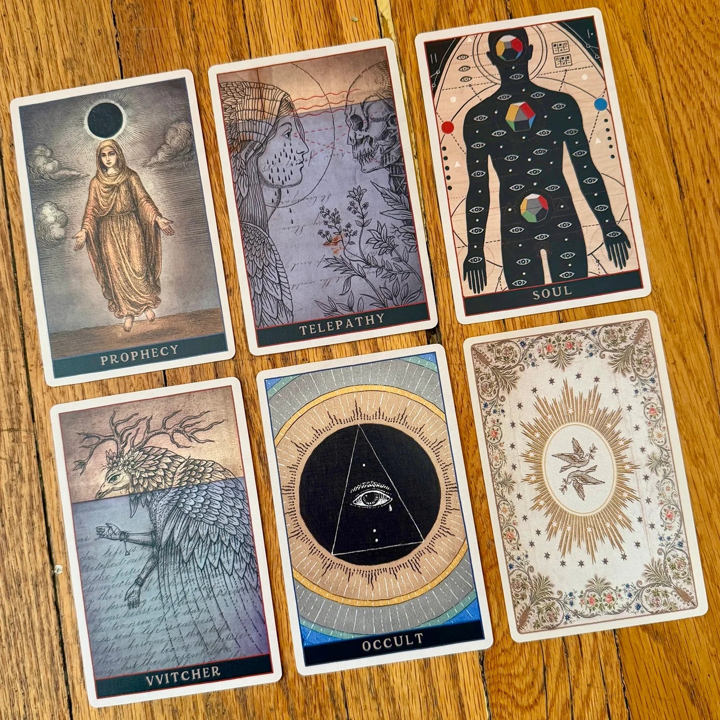 Set of tarot cards with various designs and text on a wooden surface