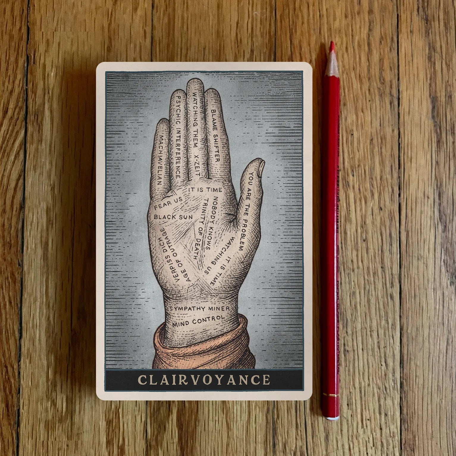 Notebook with a palmistry design and 'Clairvoyance' text on a wooden surface with a red pencil.