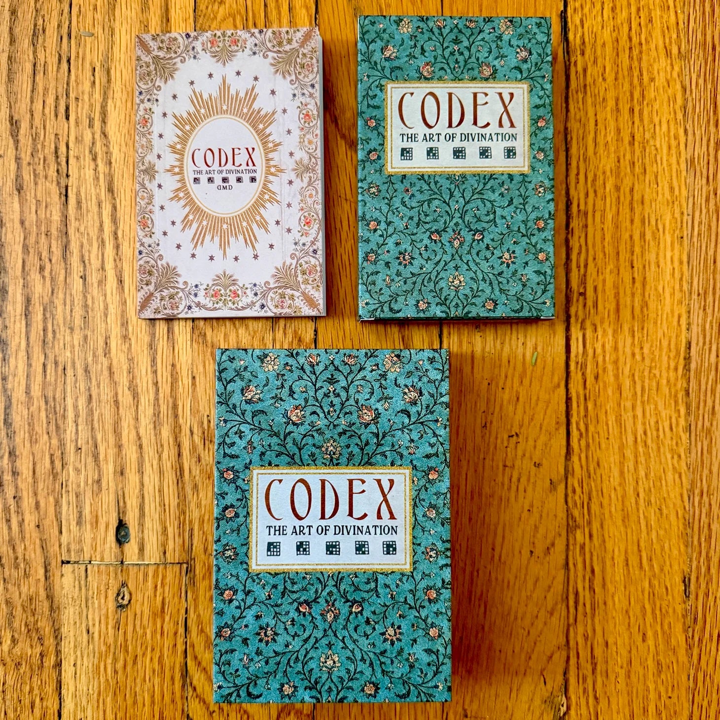 Three 'Codex' books on a wooden surface with decorative covers.