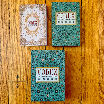 Three 'Codex' books on a wooden surface with decorative covers.