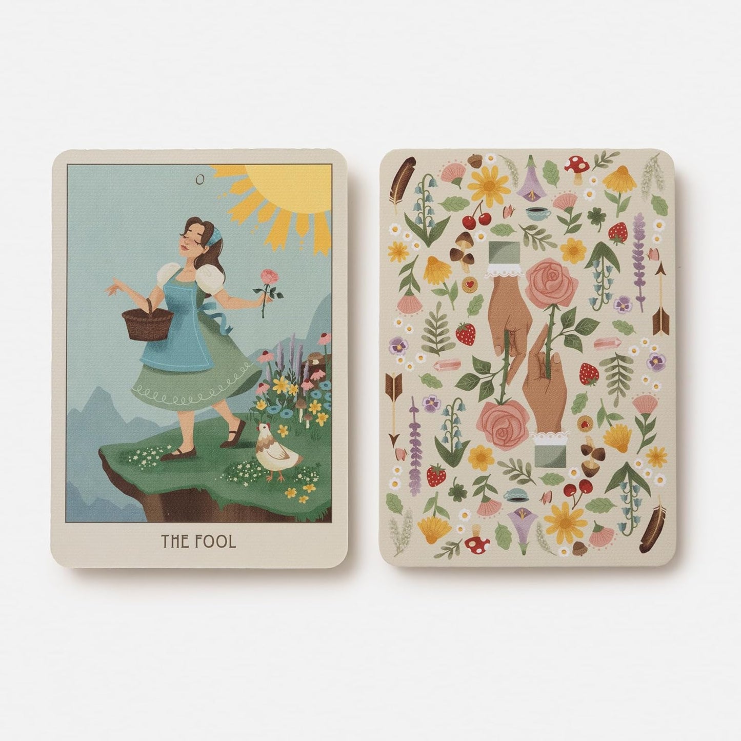 Two tarot cards, one featuring 'The Fool' with a woman in a garden and the other with floral and nature-themed illustrations.