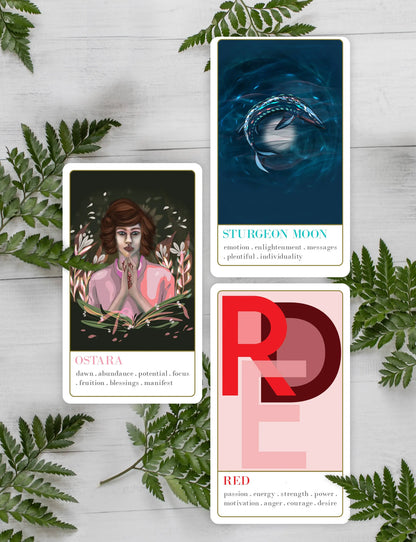 Wanderlust collection oracle deck Three tarot cards on a wooden surface with leaves around them