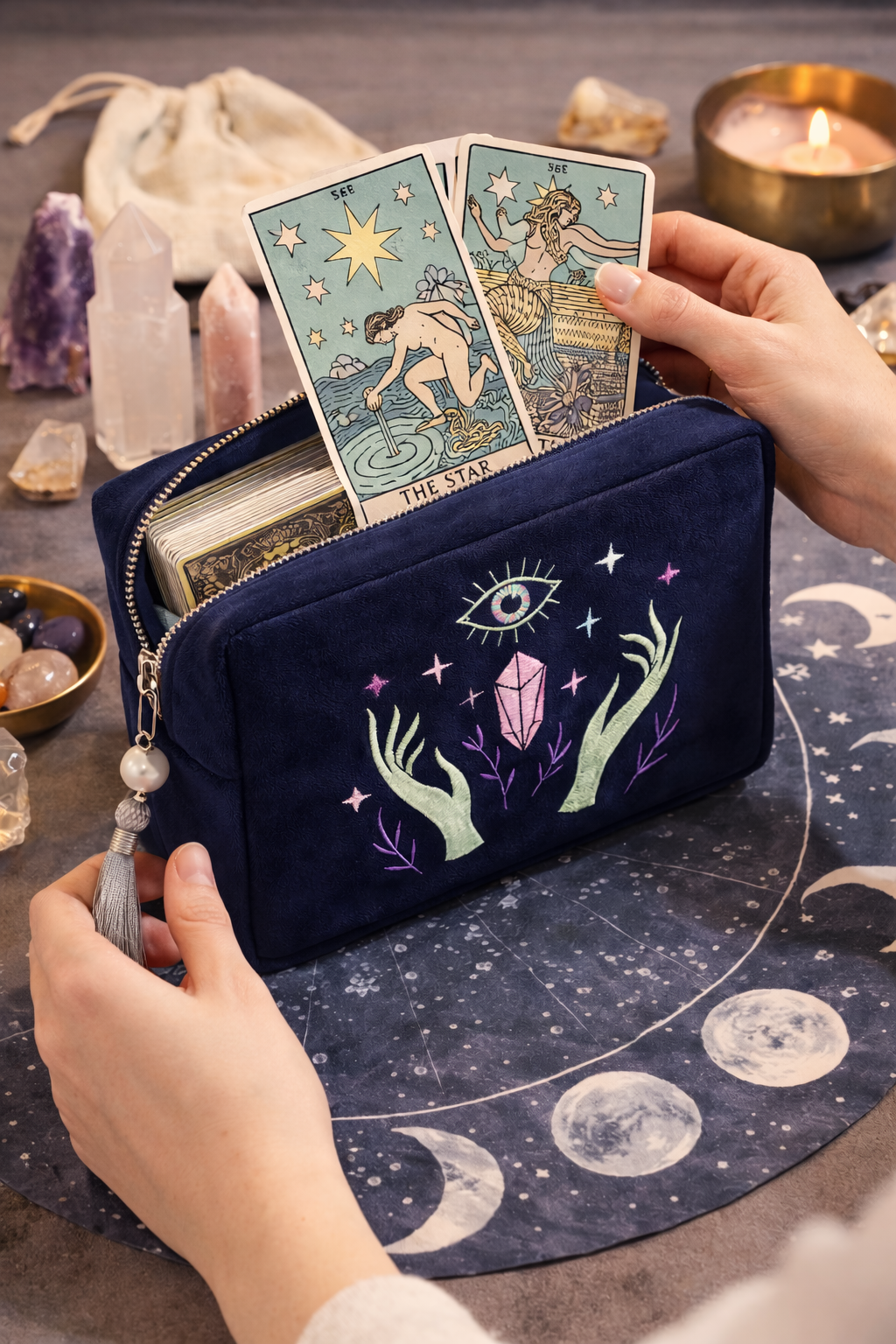 Navy blue pouch with tarot card designs and celestial elements on a table with tarot cards and crystals.