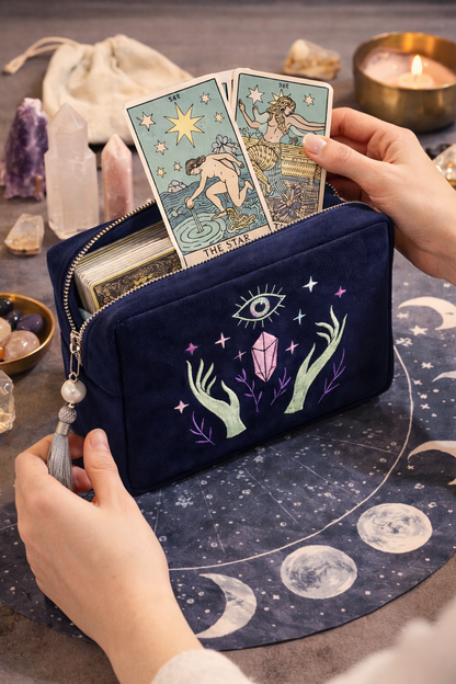 Navy blue pouch with tarot card designs and celestial elements on a table with tarot cards and crystals.