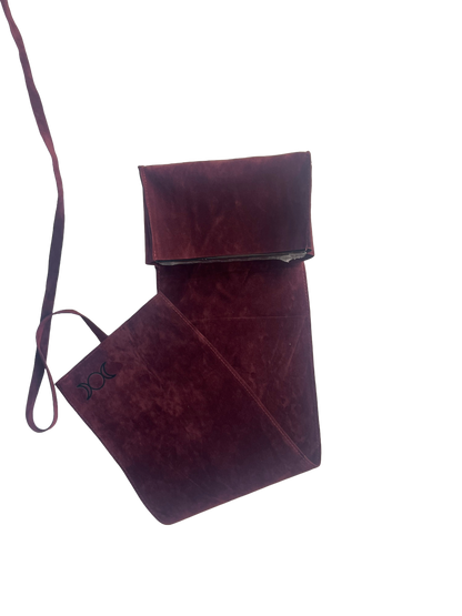 Burgundy leather bag with strap on a white background