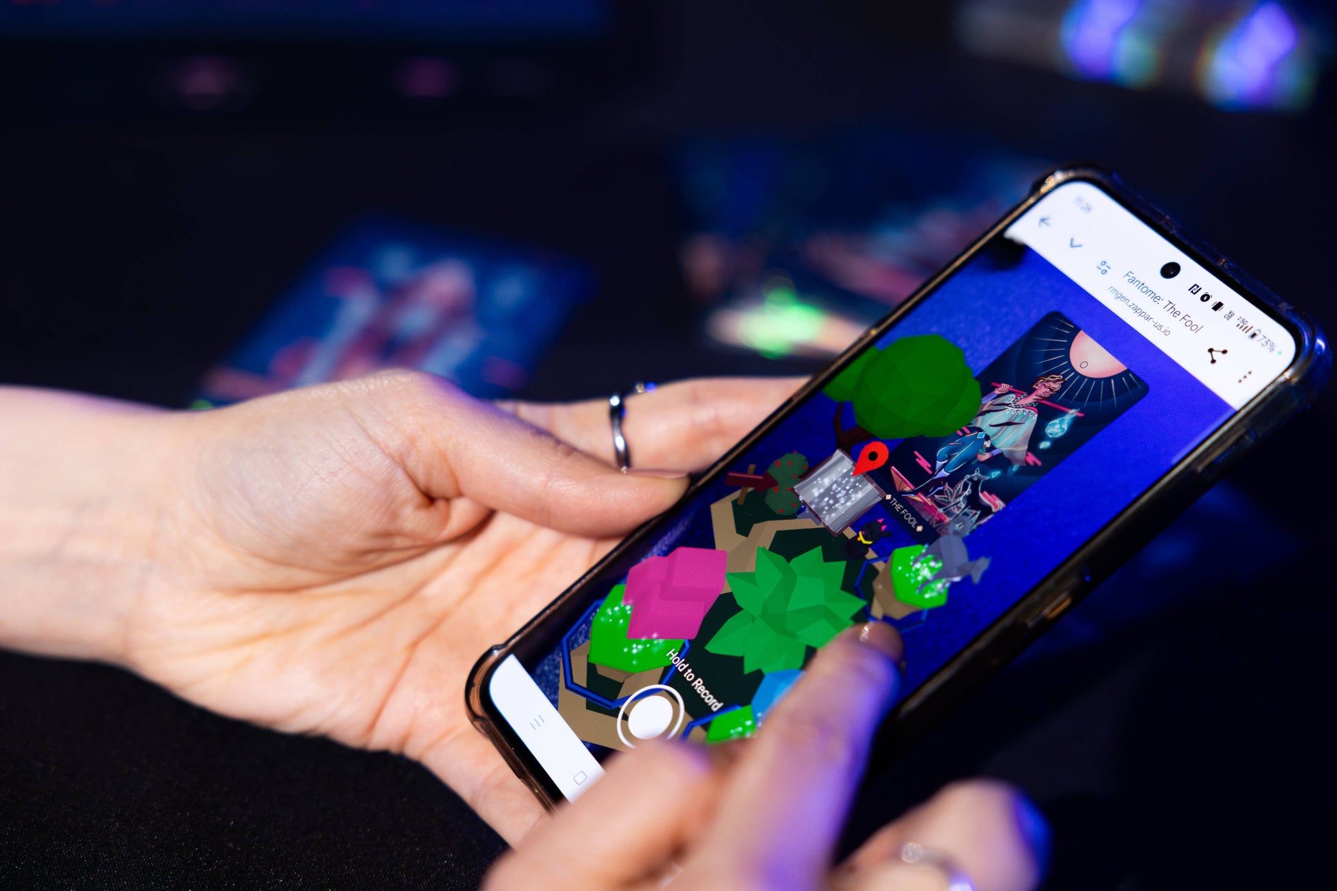 Person holding a smartphone with a colorful app interface on a dark background