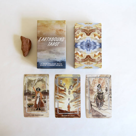 Earthbound Tarot cards with tarot cards and a stone on a white background