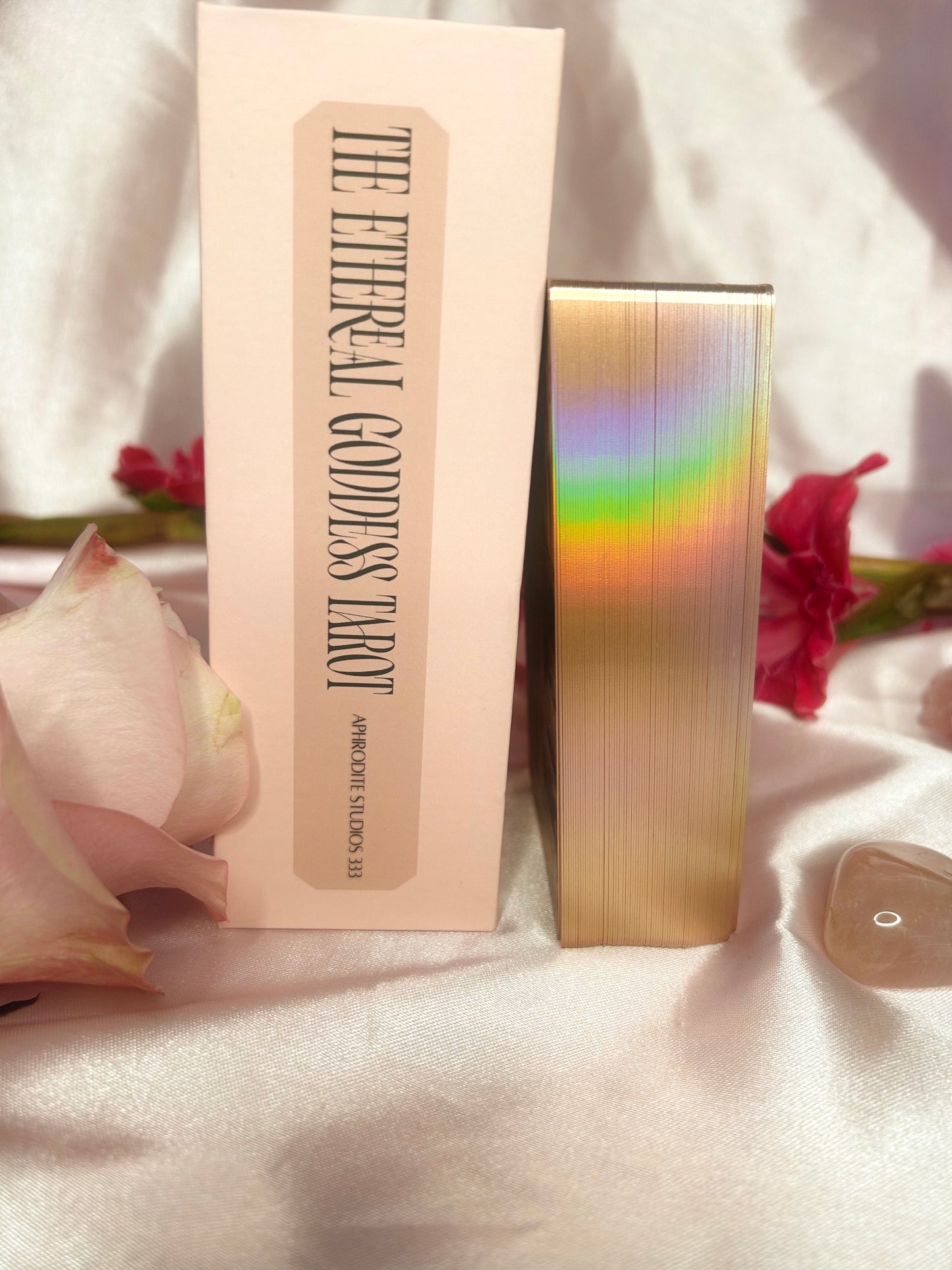Ethereal Goddess tarot deck showing the spne of the box and rainbow gold gilding on the edges of the cards. Surrounded by silk and rose petals. Available from Oneness Emporium