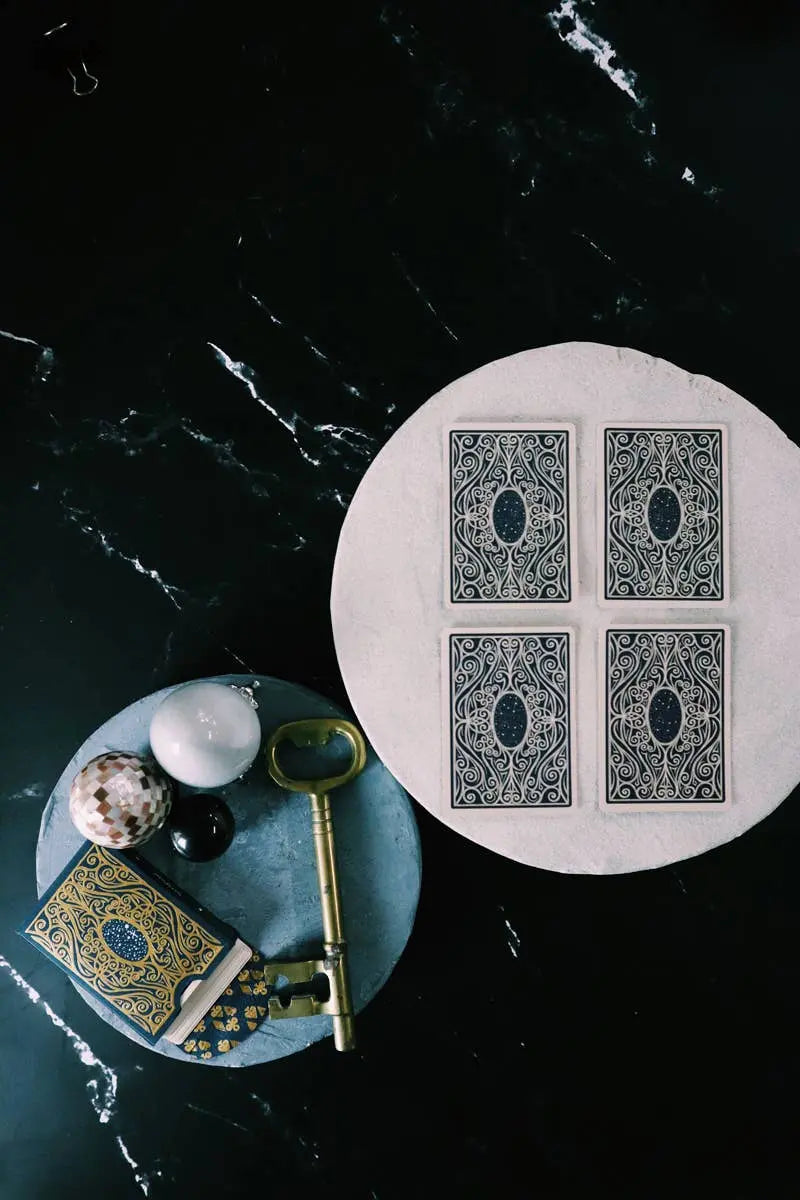 Decorative items including a key, book, and spherical object on a dark surface with tarot card designs.