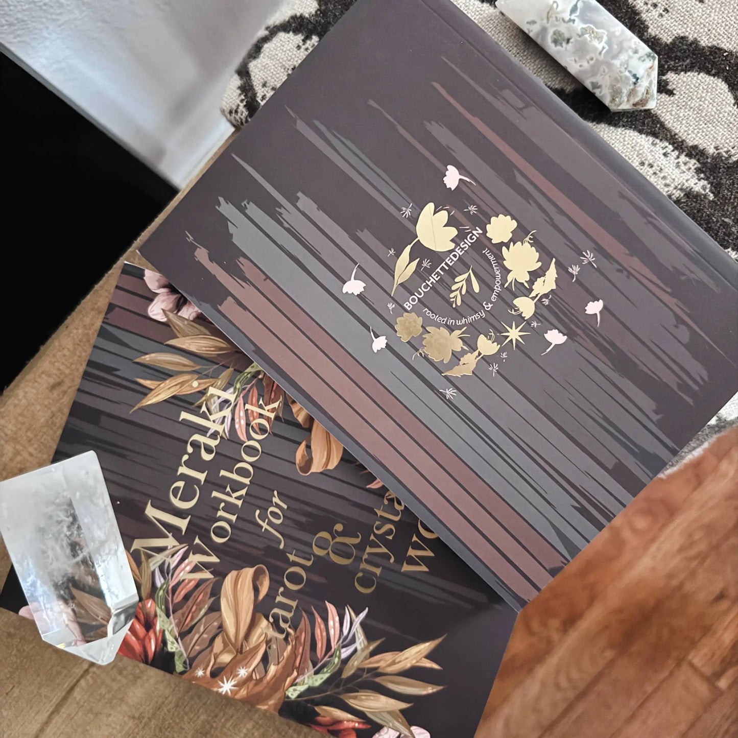 Dark workbook with floral design and text on a textured surface Meraki workbook for tarot and crystal work 