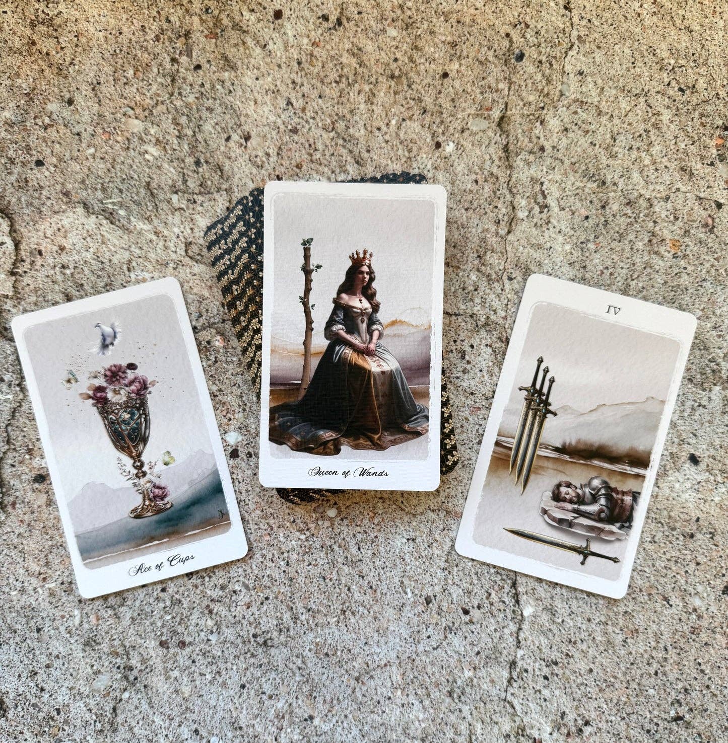 Three illustrated tarot-style cards are arranged on a rough stone surface. The center card shows a crowned queen seated on a throne, flanked by a card with a vase of flowers labeled 'Ace of Clubs' and another with swords and a body labeled 'Four'.