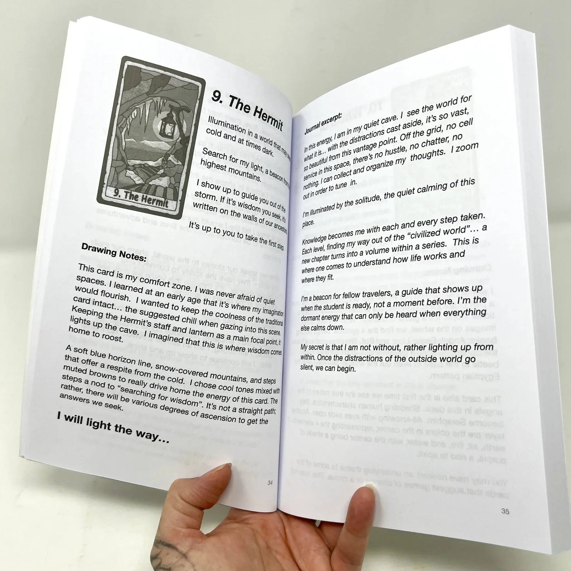Open book with tarot card illustration and text held by a hand