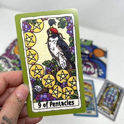 Card with a rooster and pentacle symbols held by a hand, with other cards in the background.