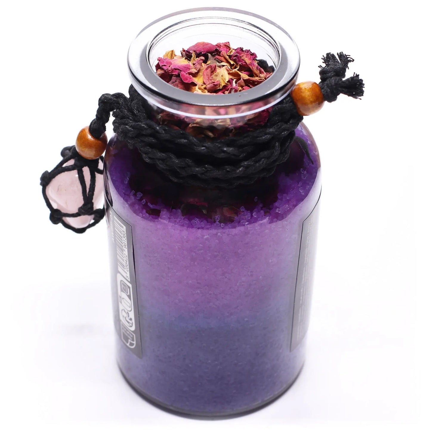 Purple glass jar with a lid containing dried flowers, tied with black cord and wooden beads on a white background.