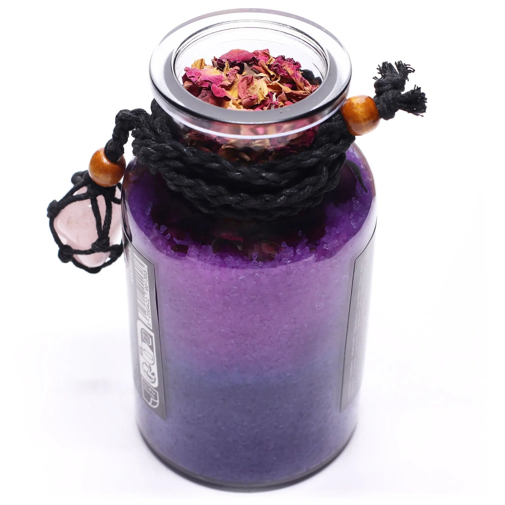 Purple glass jar with a lid containing dried flowers, tied with black cord and wooden beads on a white background.