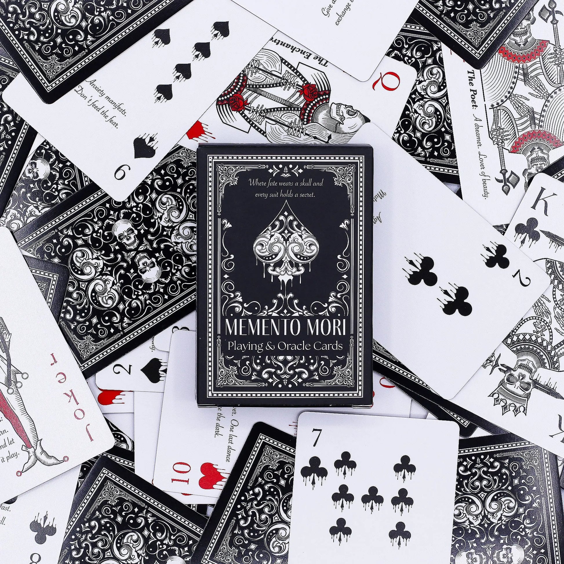 Memento Mori playing cards with black and white design on a scattered deck of cards.