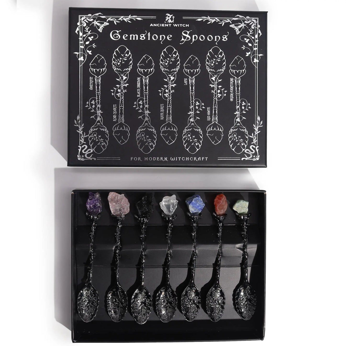 Set of gemstone spoons in a black box with decorative design and text.
