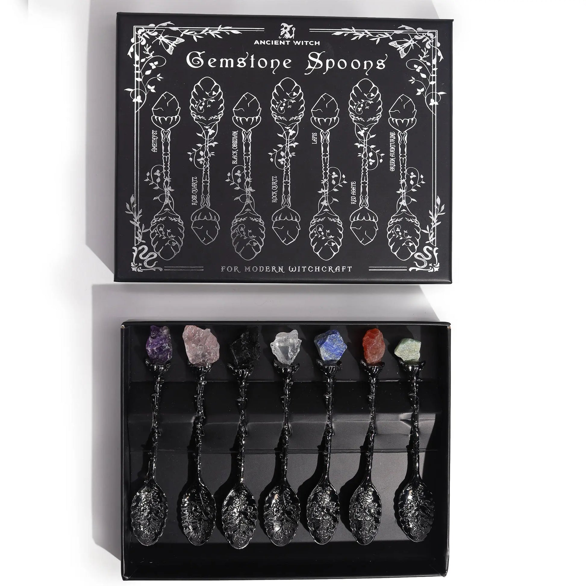 Set of gemstone spoons in a black box with decorative design and text.