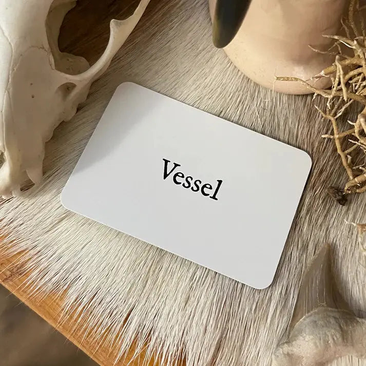 Card with 'Vessel' text on a wooden surface with natural elements