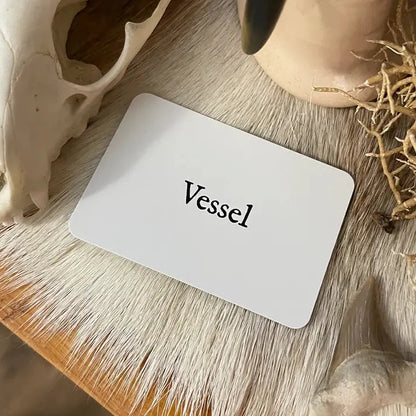 Card with 'Vessel' text on a wooden surface with natural elements